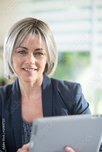 the portrait of a woman of 50 years who works with a tablet