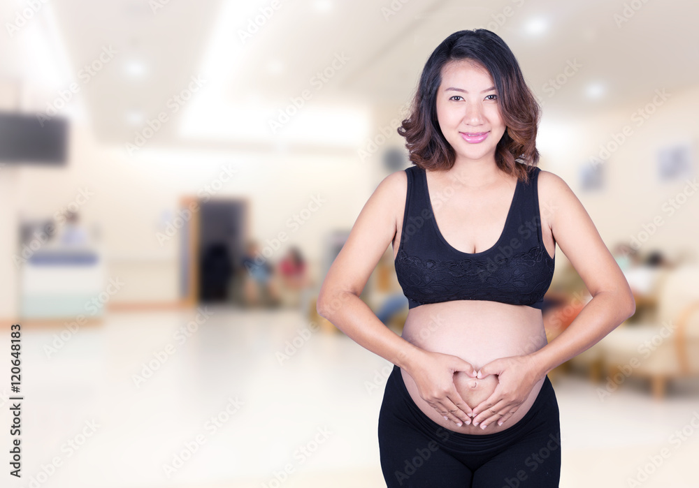 Pregnant Woman holding her hands in a heart shape on her belly i