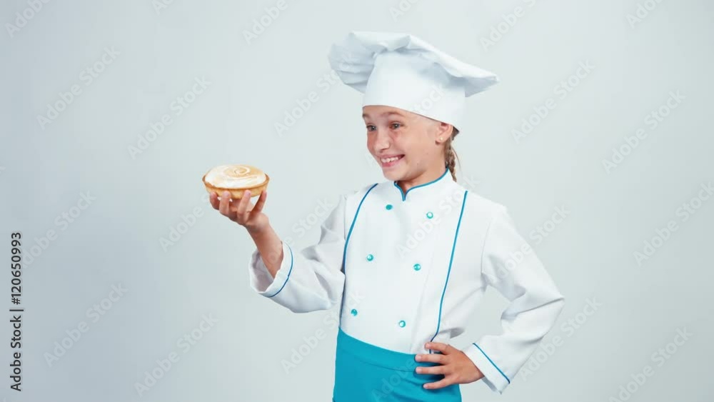 Baker holding in her hands little cake with cream and gives you it. Chef 7-8 years smiling at camera. Isolated on white Baker holding in her hands little cake with cream and gives you it. Chef 7-8 years smiling at camera. Isolated on white