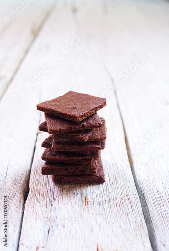 Close up of a stack of crunchy wafer thin brownies on a wooden table.