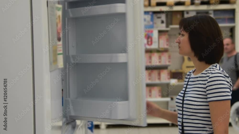 Woman looking over several fridges to choose the best one. Shopping in the store of household appliances Woman looking over several fridges to choose the best one. Shopping in the store of household appliances