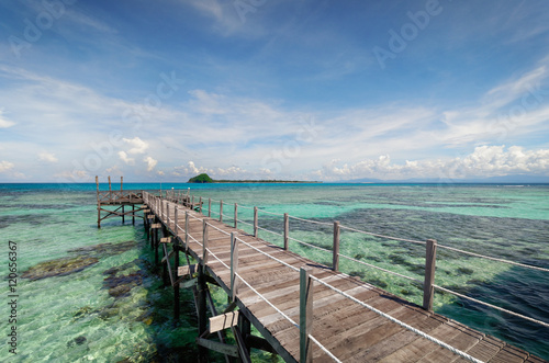 Wooden pier extending into the ocean over sea and corals. © photomagically