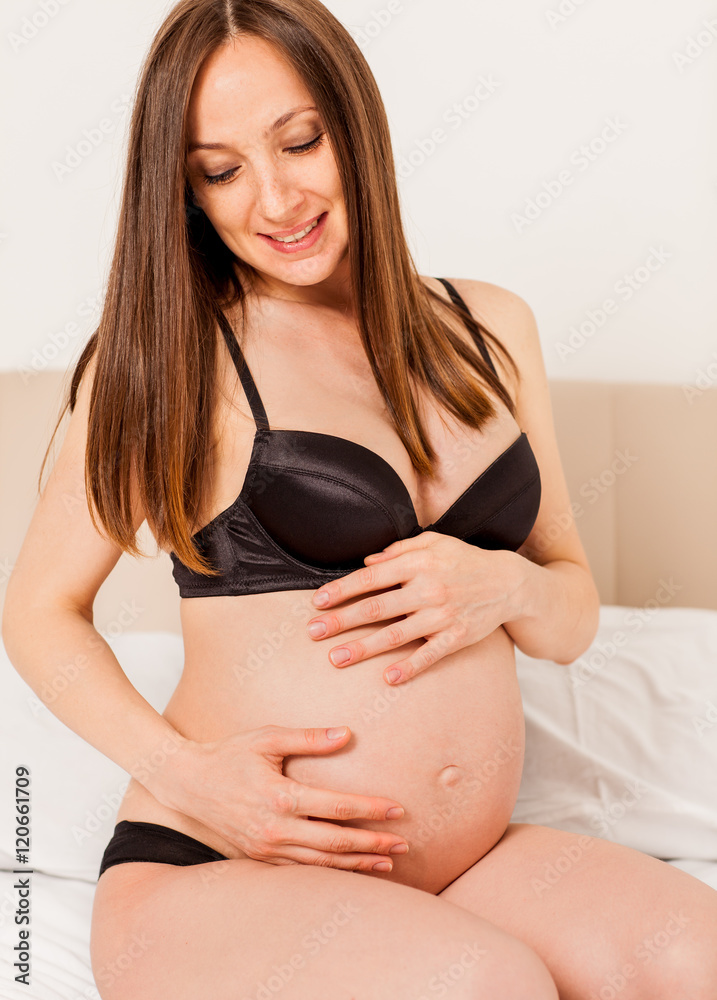 Foto Stock Pregnant woman with lingerie on bed | Adobe Stock