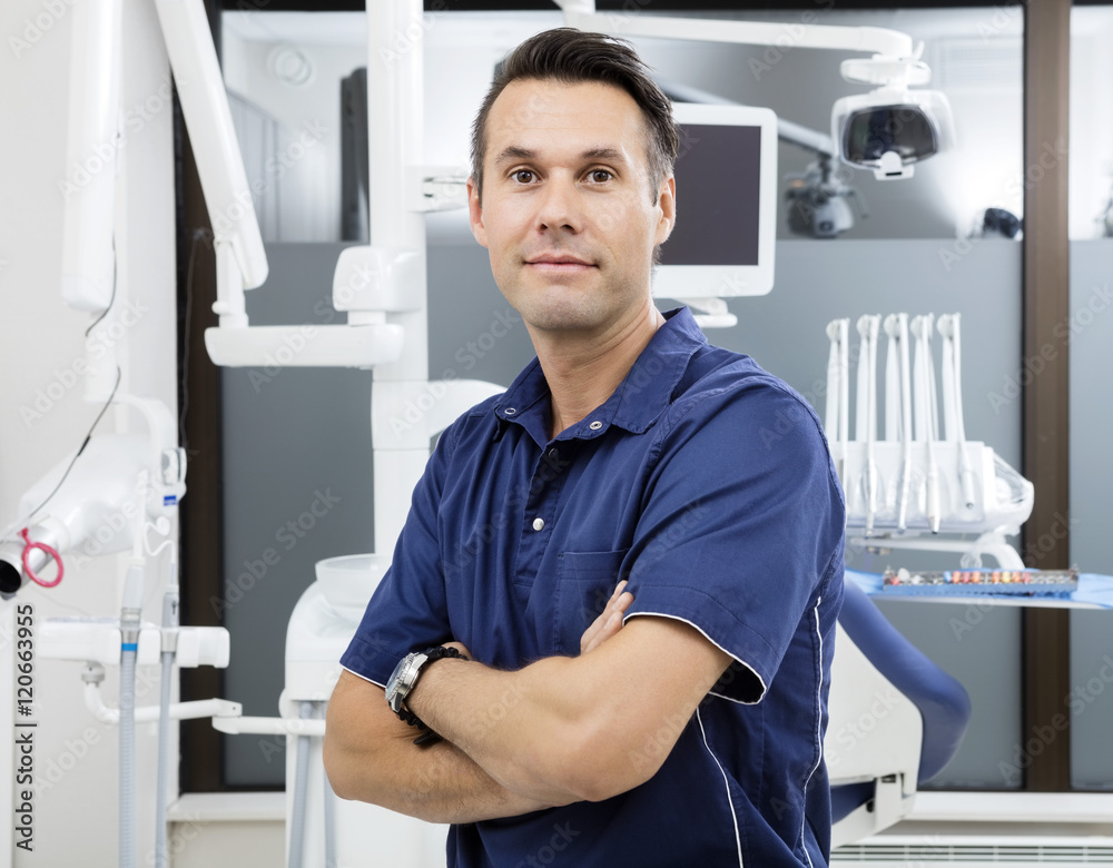 Confident Male Dentist With Arms Crossed At Clinic