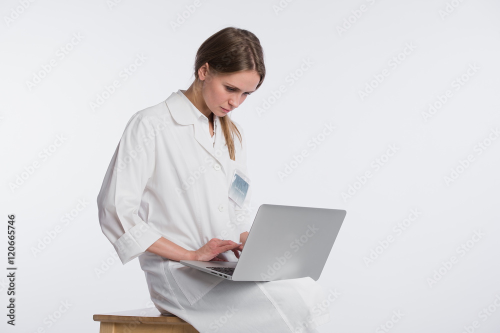 Smiling female doctor working on her laptop against a white background Smiling female doctor working on her laptop against a white background