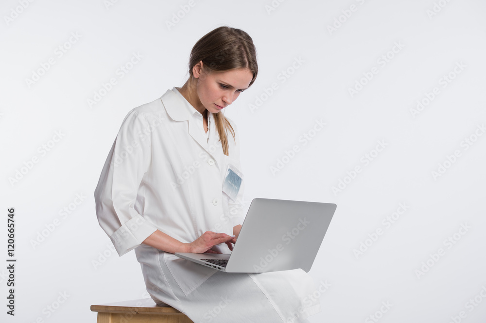 Smiling female doctor working on her laptop against a white background