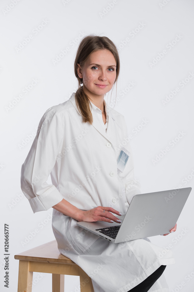 Smiling female doctor working on her laptop against a white background Smiling female doctor working on her laptop against a white background