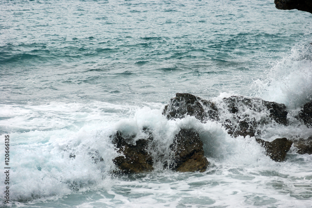 Fototapeta premium A small sea wave crashing on the rocks near the shore