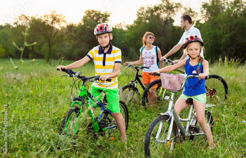 Family on bicycles on the grass field photo