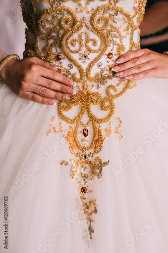 Bride in crown sitting in a beautiful white dress decorated yellow beads, hands with a wedding ring with a jewel of a close-up. Morning of the bride. Wedding day. 