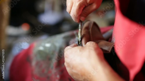 Calzolaio al Lavoro nella sua bottega artigianale. Attaccatura della suola ad un mocassino.  photo