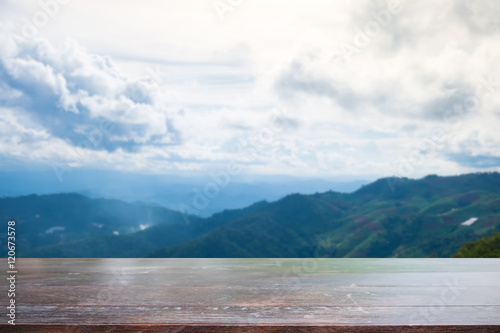 wooden desk space and mountains with sky. © Prathankarnpap
