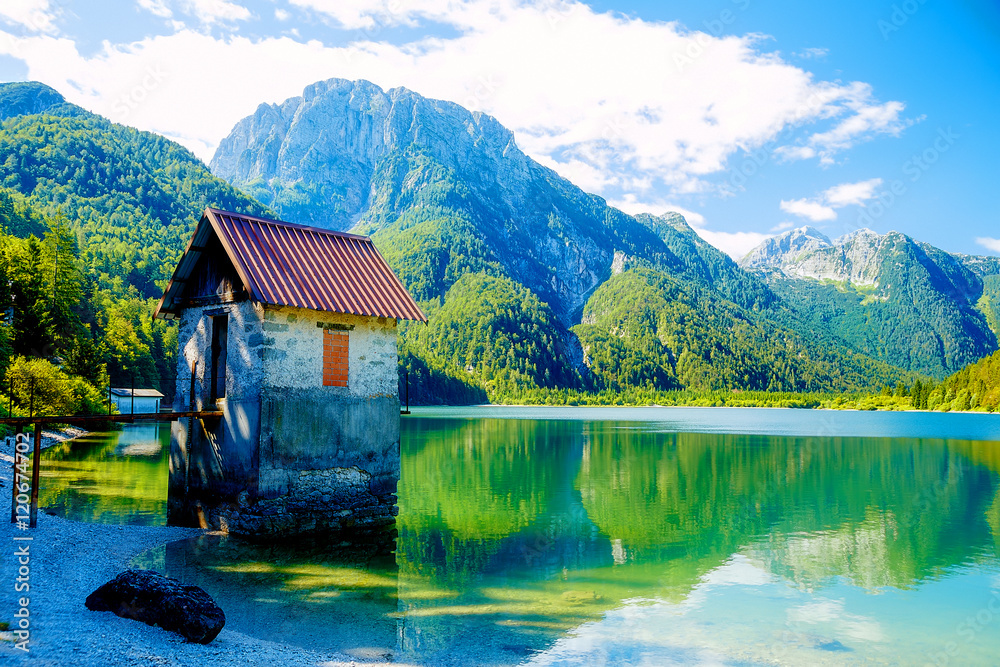 small building at a beautiful lake surrounded by stunning mountain landscape.