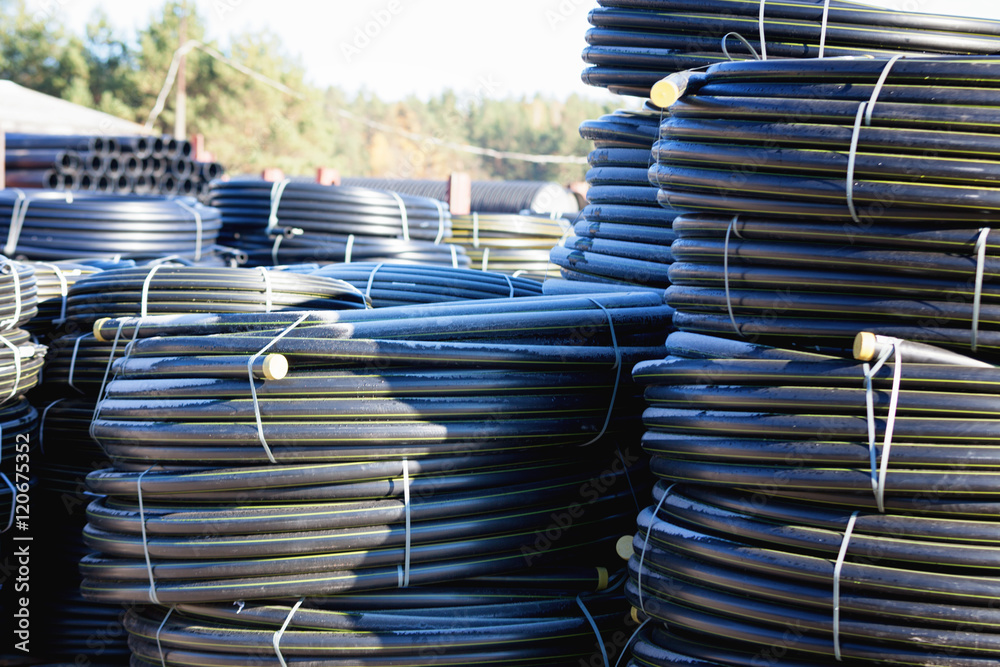Fototapeta premium stacks of black pvc plastic pipe outdoors with selective focus
