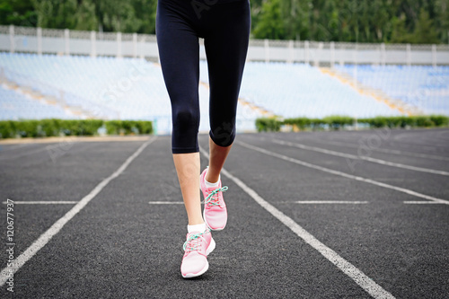 Woman running in pink sneakers on a stadium