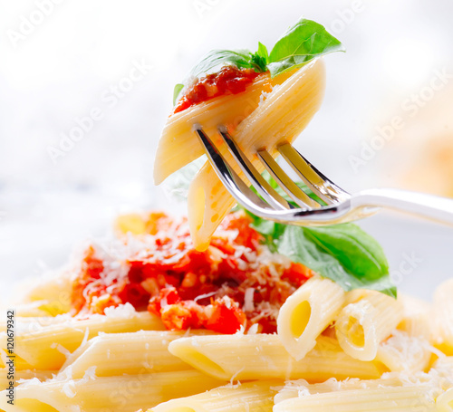 Pasta Penne with Bolognese sauce, Parmesan cheese and Basil on a Fork