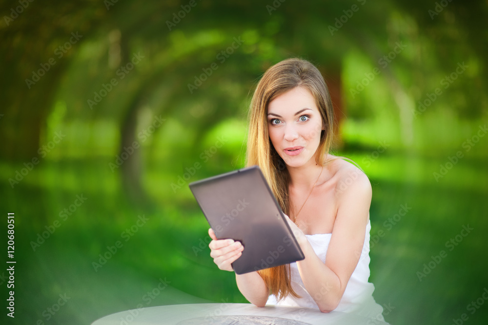 Fototapeta premium Funny woman in the park keep her tablet
