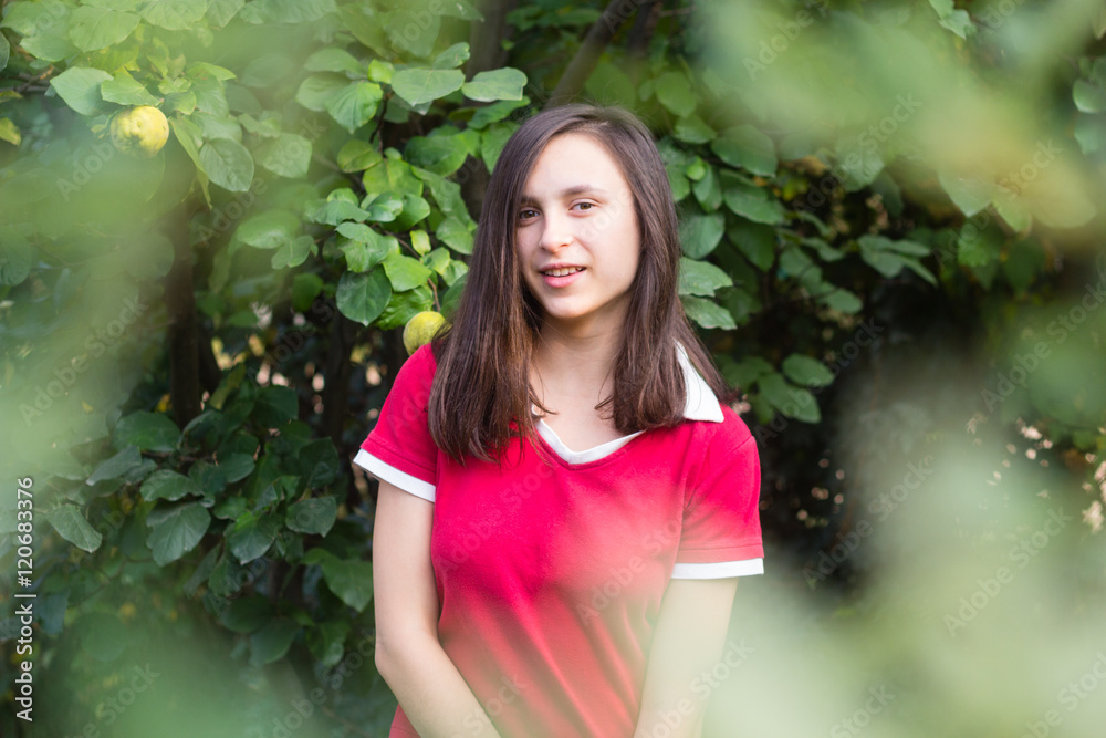 Portrait of teenage girl with dark hair near tree in orchard garden Portrait of teenage girl with dark hair near tree in orchard garden