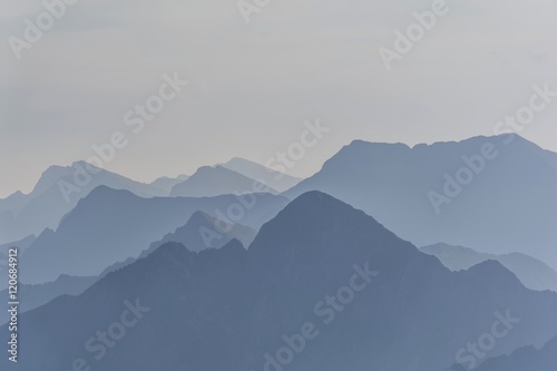 Silhouette of blue mountains in the fog. View of Moldoveanu peak, the highest peak from Romanian Carpathian Mountains range. Seamless background. photo