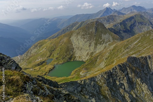 Mountain lake with crystal clear water of emerald color. Landscape from Capra Lake in Romania and Fagaras mountains in the summer