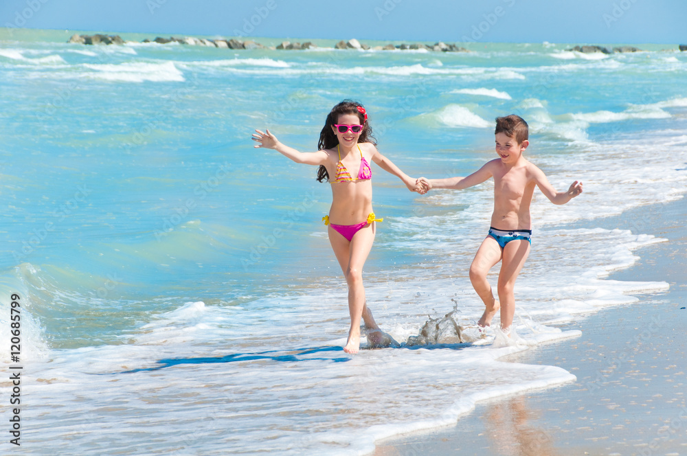 Children running on the beach holding hands
