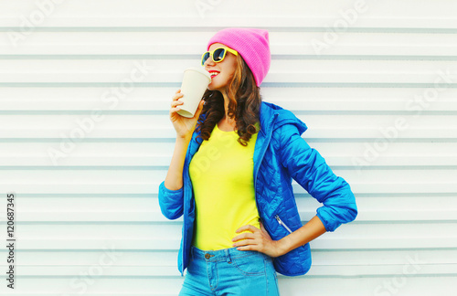 Fashion pretty woman with coffee cup in colorful clothes over wh