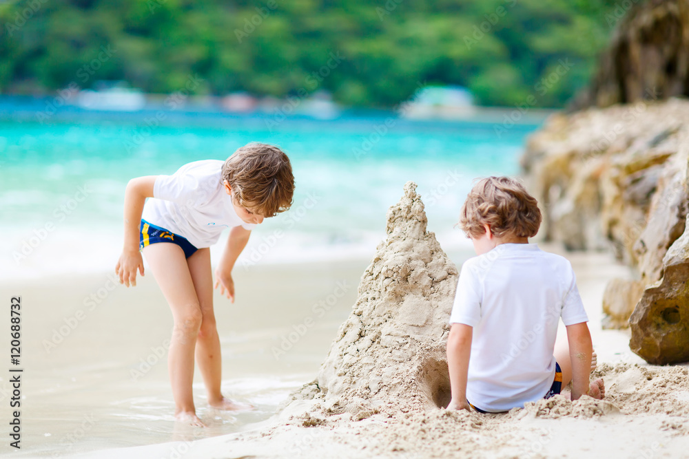 Two kid boys building sand castle on tropical beach Two kid boys building sand castle on tropical beach