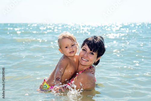 Mom and baby are swimming in the sea on summer vacation. The education and development of children.