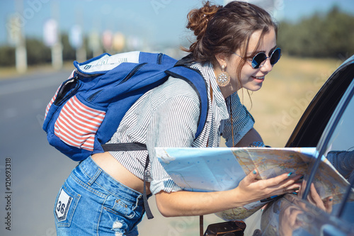 Young female hitchhiker asking a road to driver