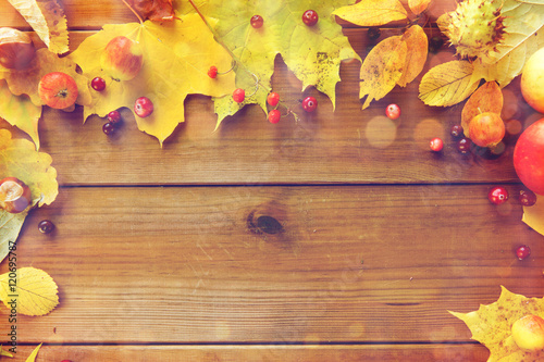 frame of autumn leaves, fruits and berries on wood