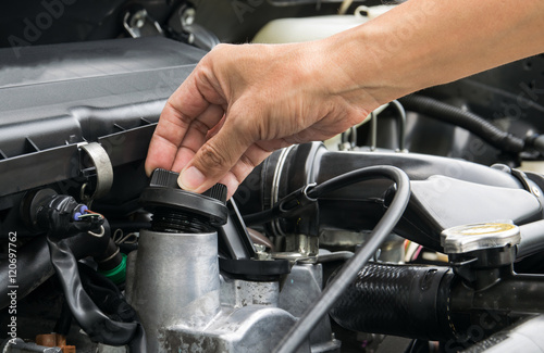 A mechanic is opening the oil cap from a car engine.