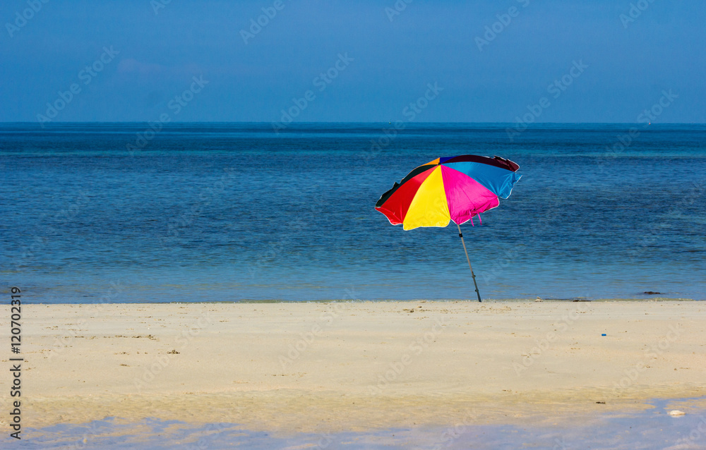 Single colourfull striped umbrellas on the beach