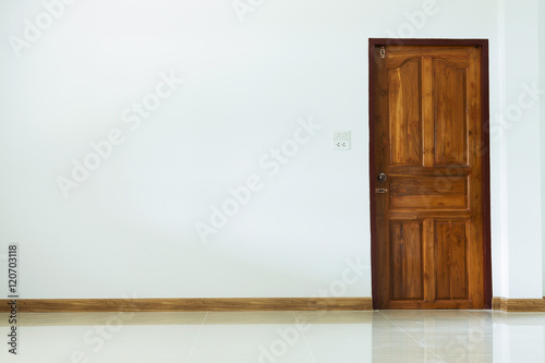 empty room interior with wooden door and white mortar wall