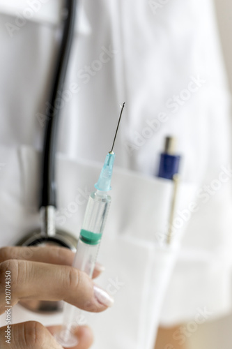 Medical doctor holding a syringe upwards