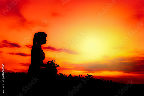 Silhouette healthy woman doing yoga exercises on the beach with sunset morning at Phuket, Thailand
