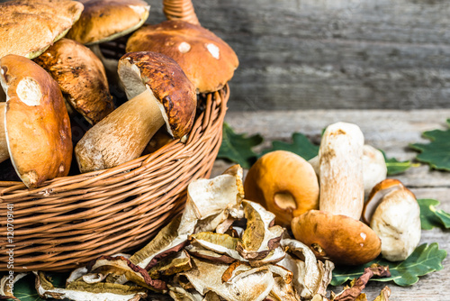 Dried mushrooms and fresh boletus mushroom in a basket on rusti