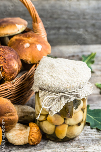 Boletus mushrooms pickled in jar on rustic wooden table, autumna
