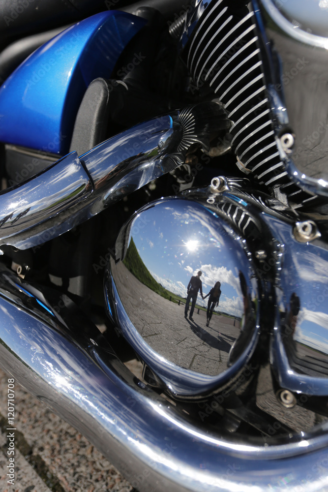 reflection of young couple in motorbike motor