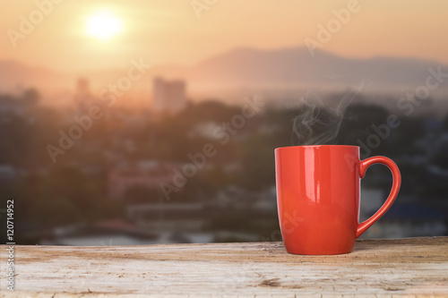 ..a cup of hot coffee on a rustic table against the morning rising sun . photo
