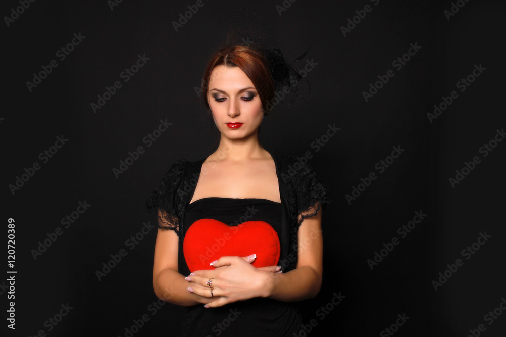 mysterious girl with a heart in his hands in a little black dress on a black background mysterious girl with a heart in his hands in a little black dress on a black background