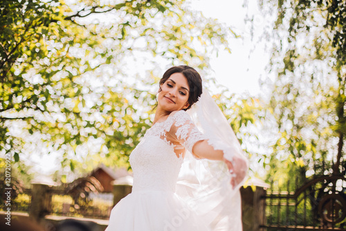 Young bride wearing gorgeous wedding dress, playing with veil.  plays a wedding dress. Dress develops in the wind. Happy bride in a wedding dress is spinning.
