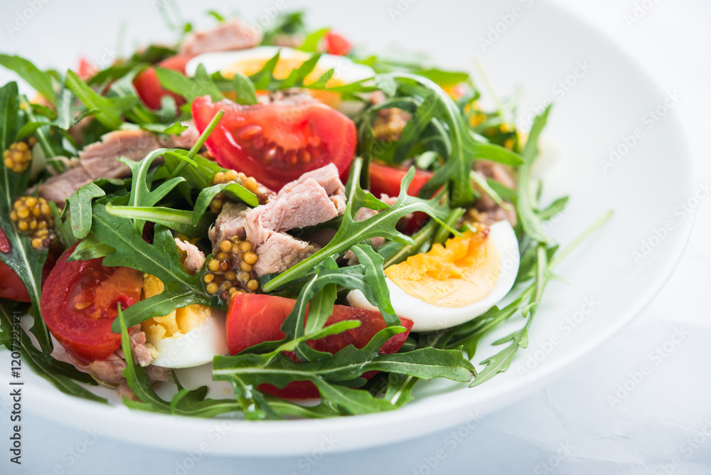 Fresh salad with tuna, tomatoes, eggs, arugula and mustard on white textured background close up. Healthy food. Fresh salad with tuna, tomatoes, eggs, arugula and mustard on white textured background close up. Healthy food.
