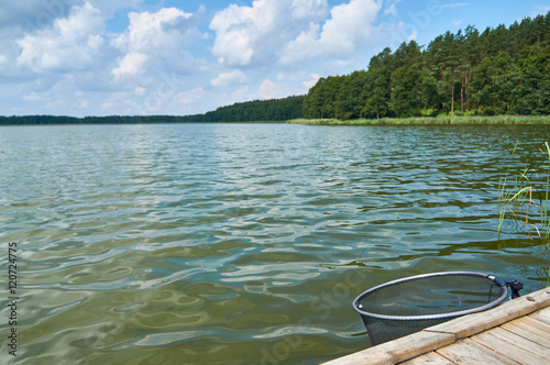 Fototapeta Naklejka Na Ścianę i Meble -  Empty footbridge with net for fish over beautiful Lemiet lake in Mazury district, Poland. Fantastic travel destination.