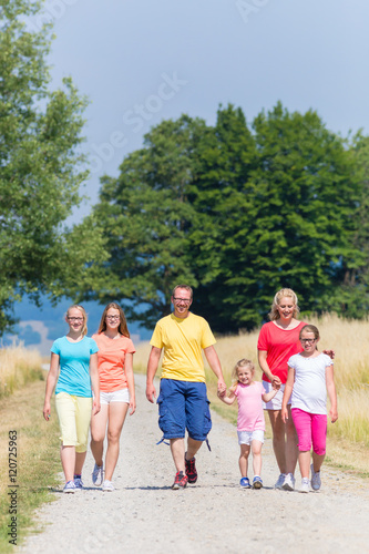 Familie macht Spaziergang im Sommer auf Feldweg in der Sonne © Kzenon