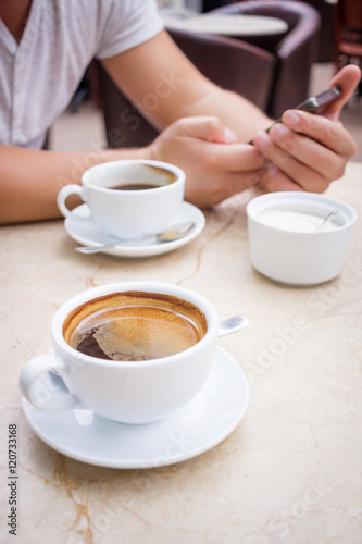 Man with smartphone at marble table with cup of coffee