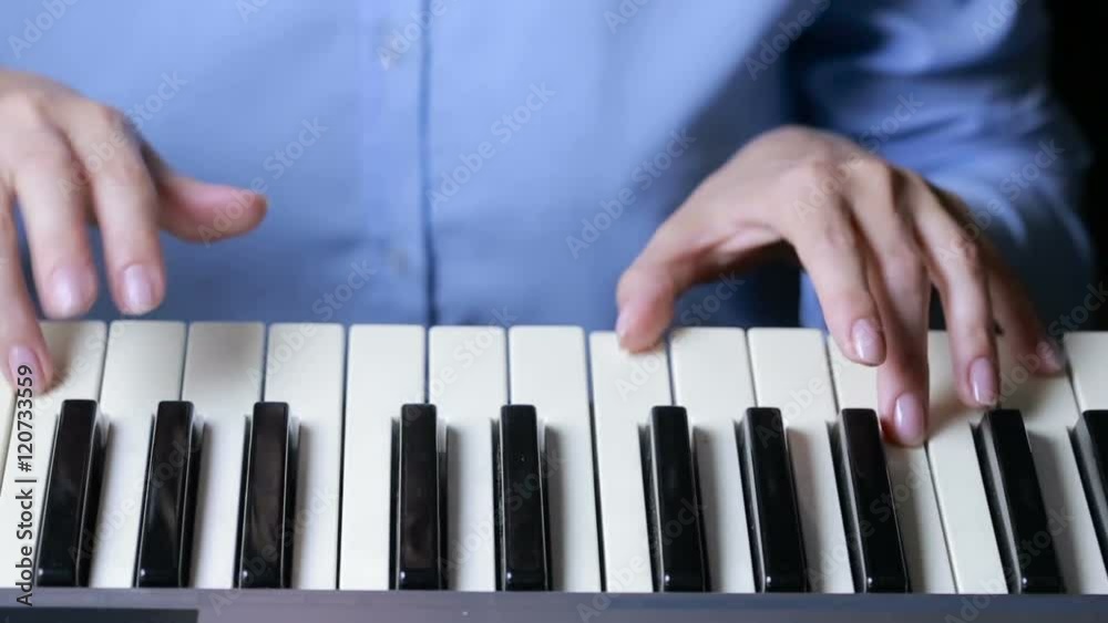 Woman hand playing a MIDI controller keyboard synthesizer close up.