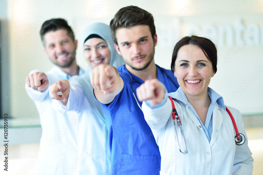 healthcare and medicine concept - attractive male doctor in front of medical group in hospital showing thumbs up healthcare and medicine concept - attractive male doctor in front of medical group in hospital showing thumbs up
