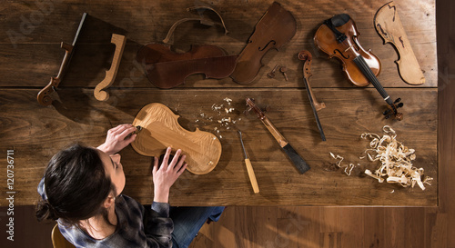 Top view. female luthier working on the creation of a violin photo