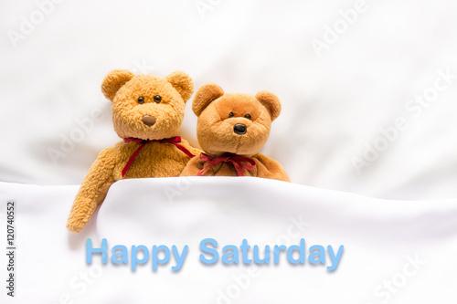 Teddy Bear lying in the white bed with message " Happy Saturday" © meen_na