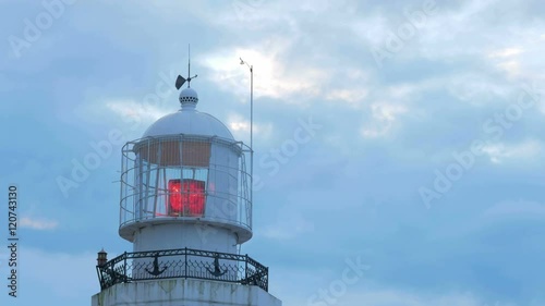 Red beacon light near the sea. Against the background of the morning sky in the clouds photo